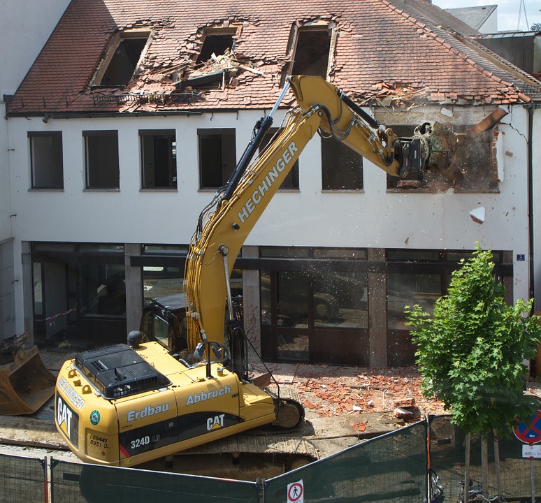 excavator demolshing the upper level of a house