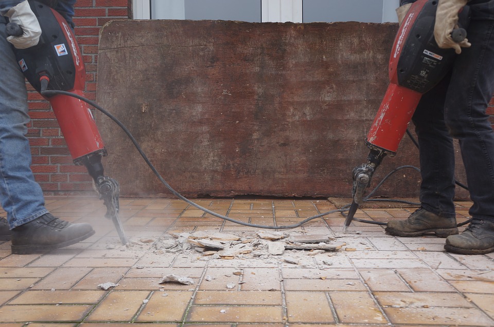 workers using jackhammers to break up and remove floor tiles