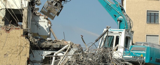 excavator with claw attachment demolishing a building